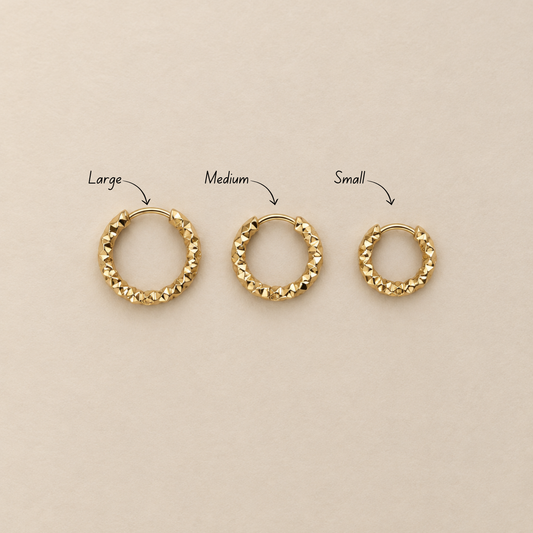 Grain Hoop örhängen i guld visade i small, medium och large på ljus bakgrund.