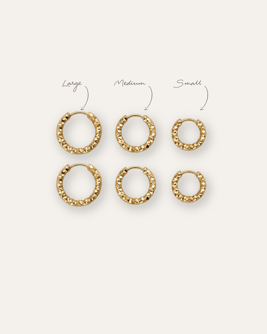 Grain Hoop örhängen i guld visade i small, medium och large på ljus bakgrund.