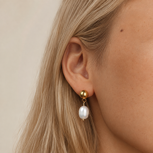 Satin Pearl Drop 316-kirurginteräksestä, 18K PVD-kultapinnoitteella, helmikorvakoru pyöreällä kullanvärisellä napilla korvassa.