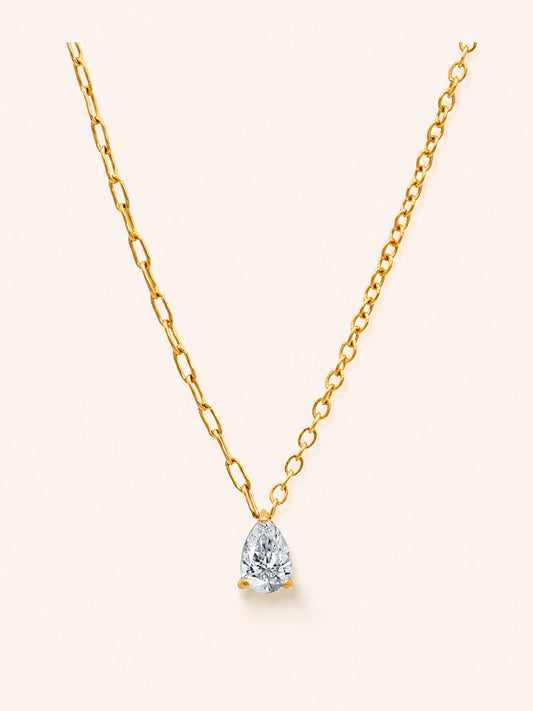 Drop Necklace i 18k PVD-guld med droppformad zircon och asymmetrisk kedja på ljus bakgrund