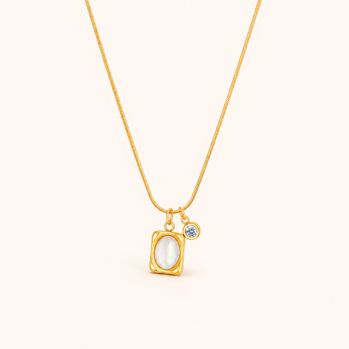 Halo Necklace i 18k PVD-guld med rektangulärt hänge, oval ljus detalj och liten klar sten på mörk bakgrund